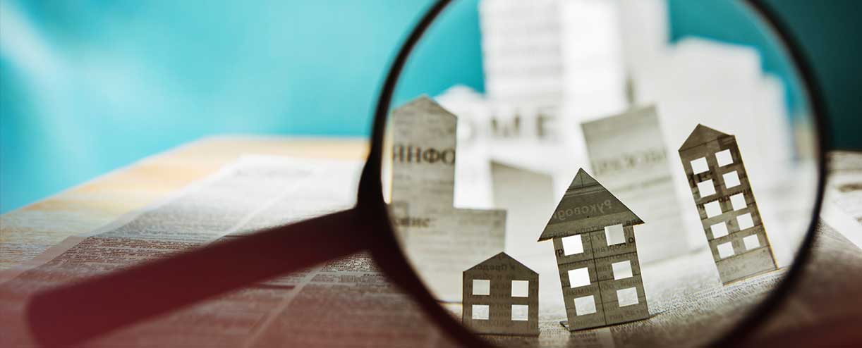 Magnifying glass showing paper houses.