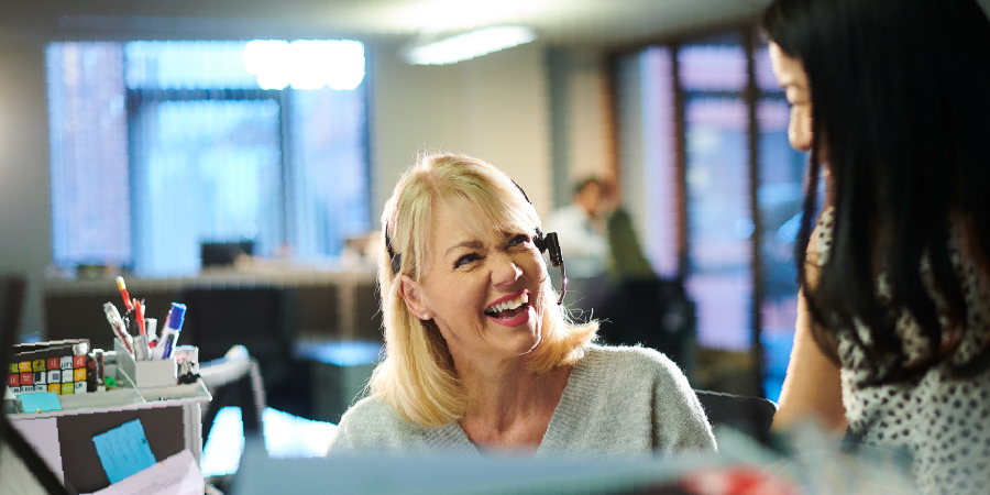 Administrative professional with headset smiling at coworker