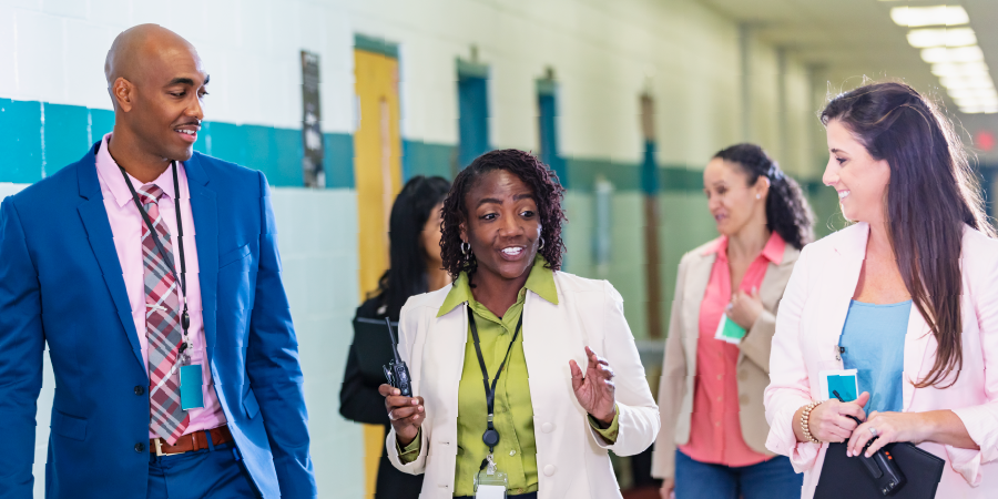 School faculty walking down a hallway and talking.